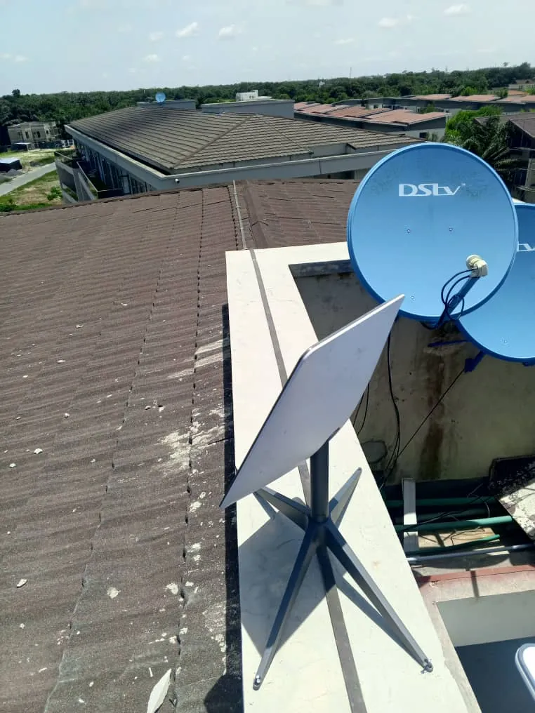 Starlink dish on a parapet beside two DStv dishes on a stone-coated roof
