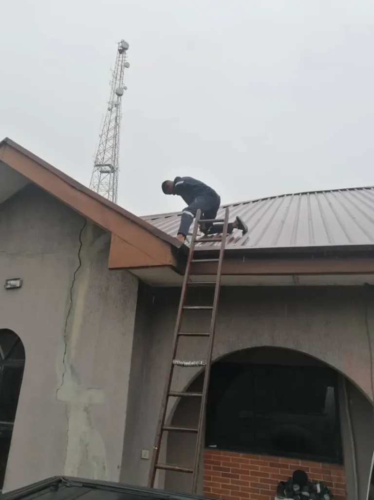 ZuraLink installer on a pitched roof fixing a Starlink dish in the rain