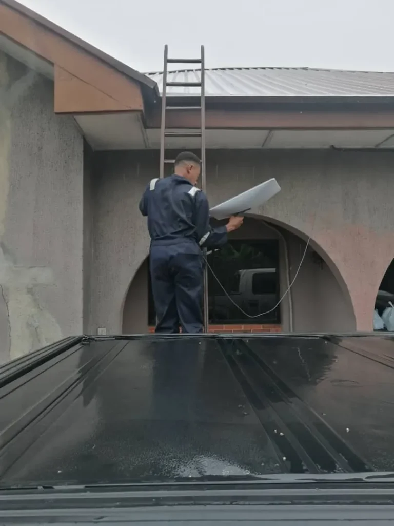 Installer at the foot of the ladder with the Starlink dish