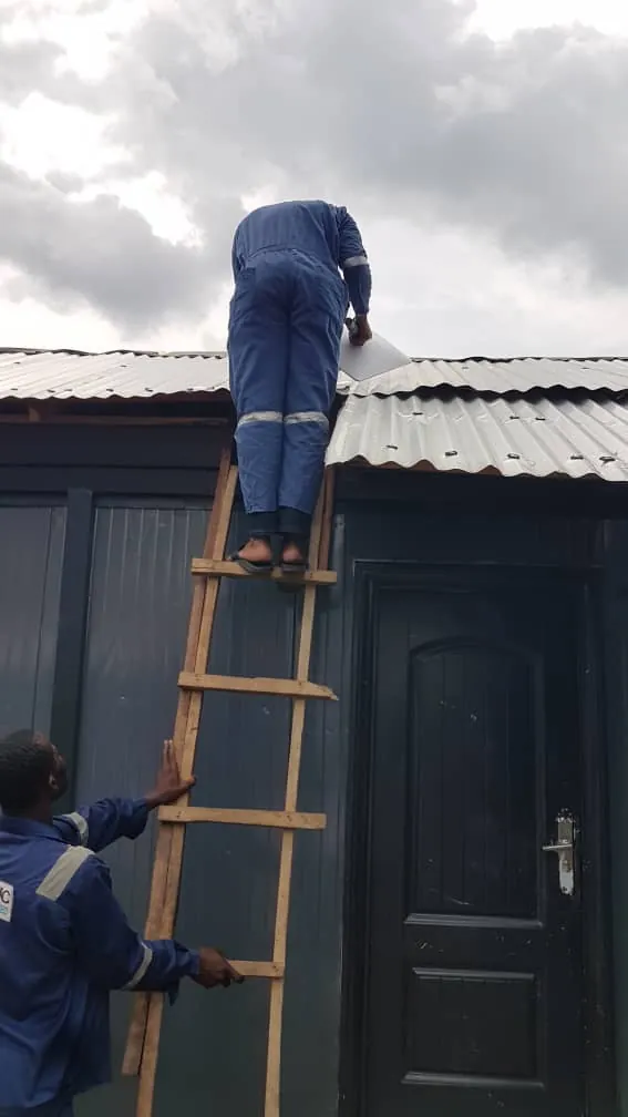 Installer at the roof edge with a colleague holding the ladder