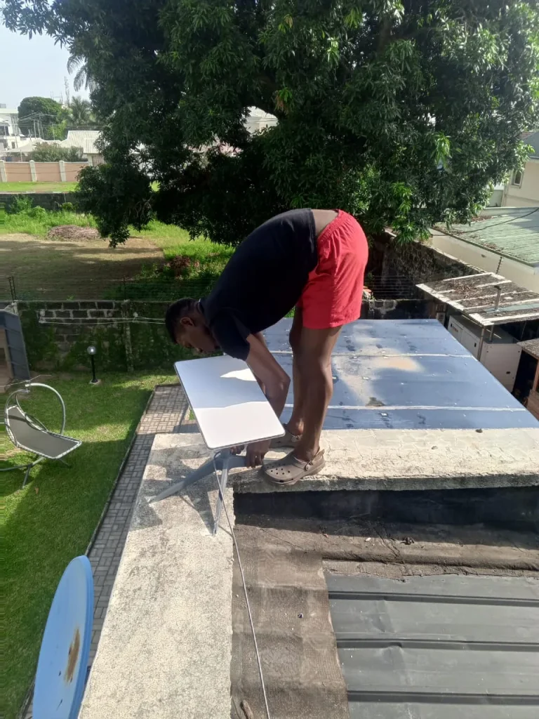 ZuraLink installer setting a Starlink dish on a flat roof above a garden