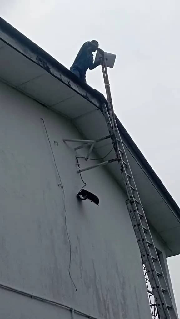 ZuraLink installer mounting a Starlink dish on a bracket at the gable of a two-storey house