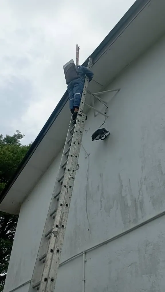 Installer on the ladder securing the Starlink bracket at the gable edge