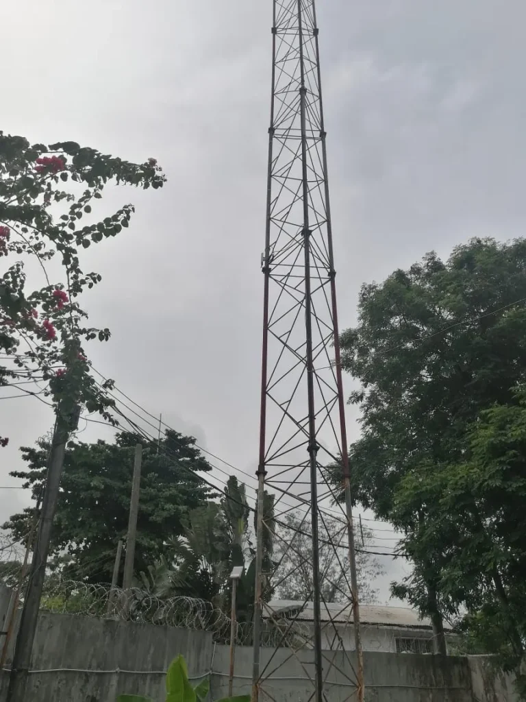 Telecom mast near the two-storey house, kept out of the dish's view