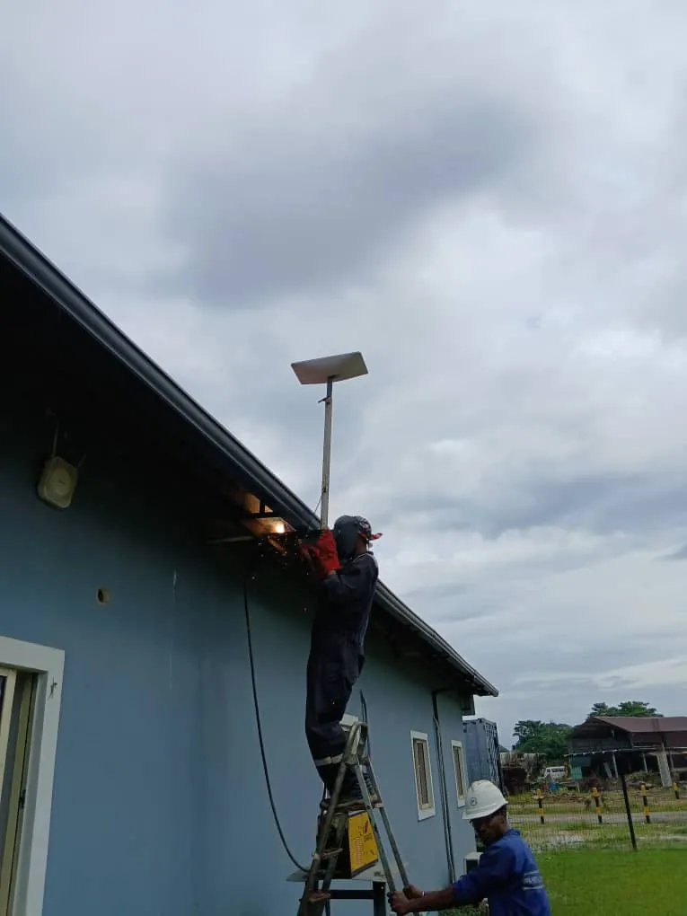 ZuraLink installer welding a Starlink pole to the roof edge of a site building