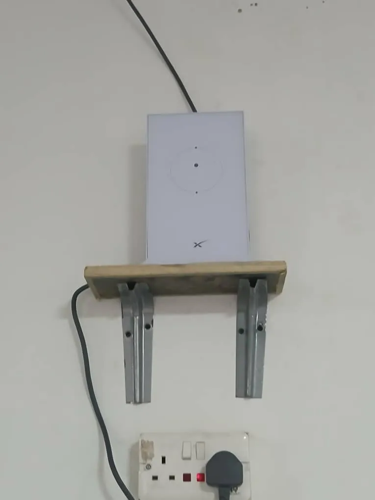 Starlink router on a wooden shelf above a socket