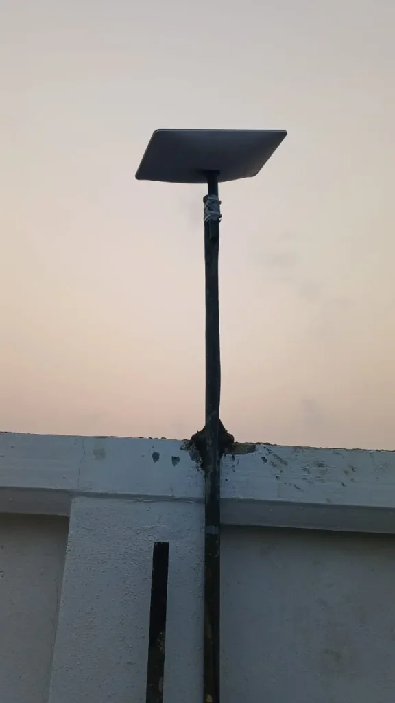 Starlink dish on a steel pole set into the roof parapet of a new commercial building