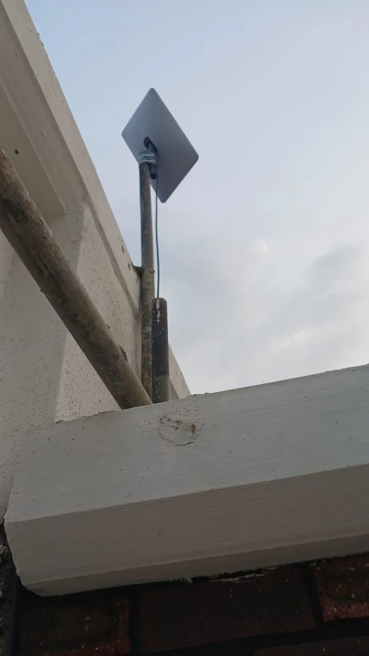 Pole-mounted Starlink dish above the parapet of the commercial building