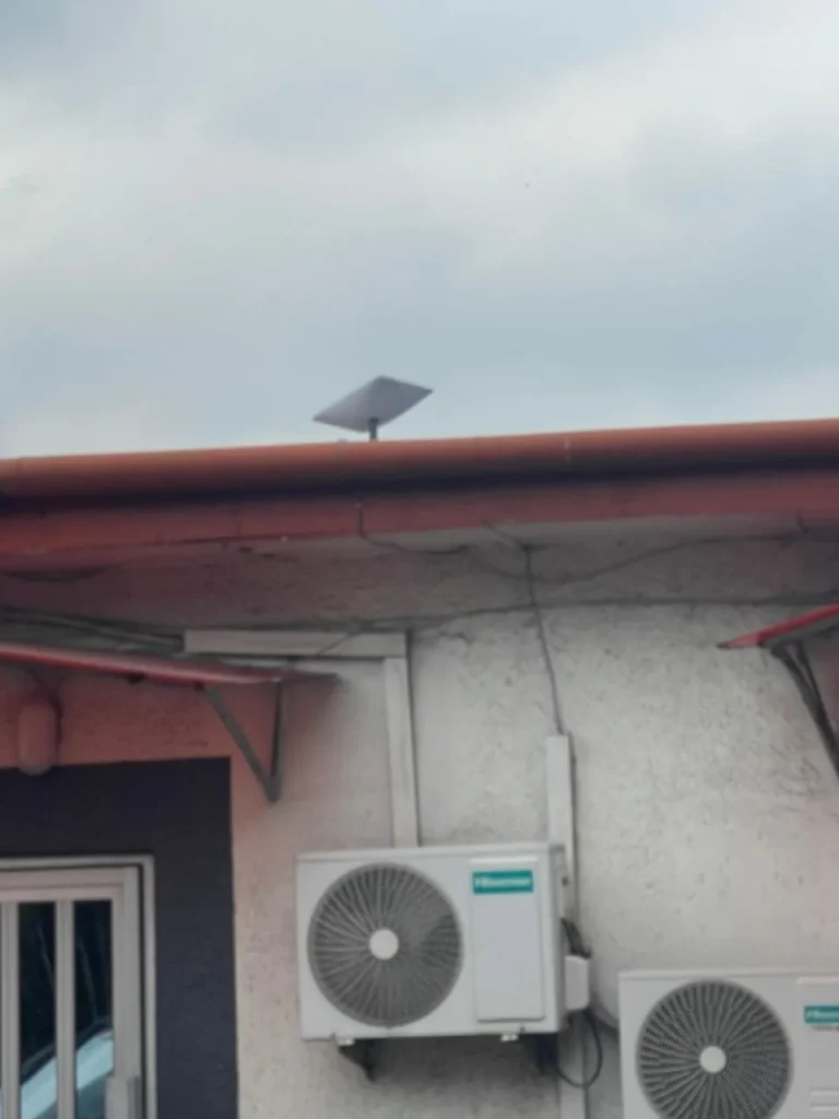 Starlink dish on a short pole at the roof edge of an office bungalow