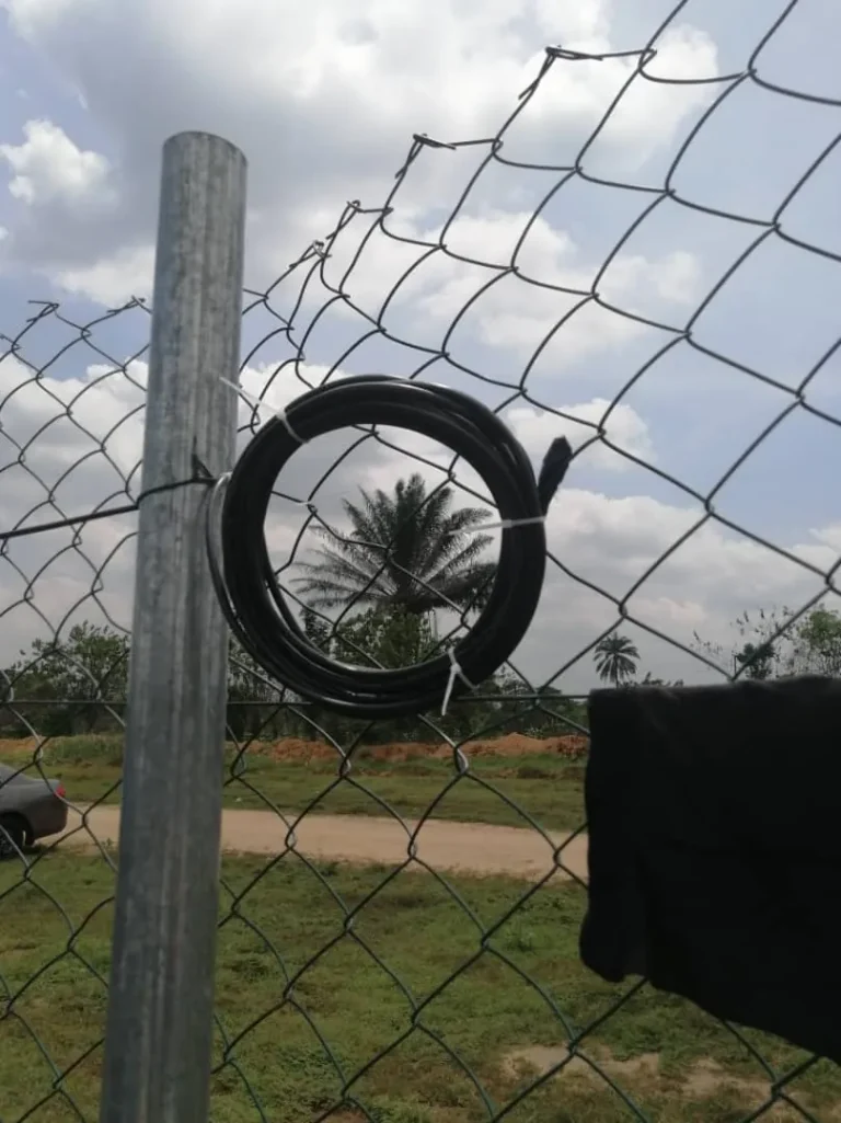 Spare Starlink cable coiled neatly on the fence pole