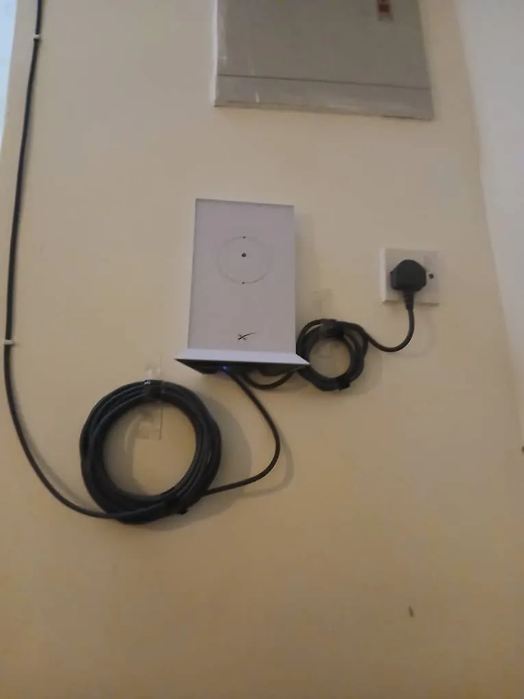 Starlink router fixed to the wall beside a socket