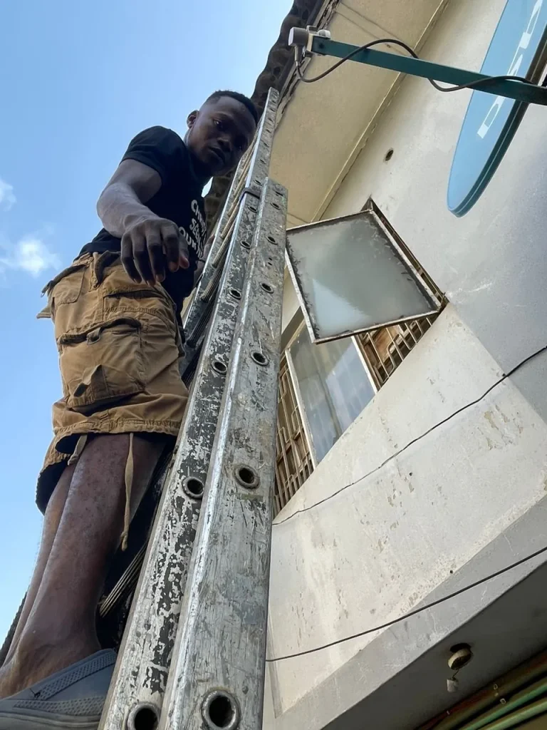 Installer on the ladder taking the Starlink cable up the wall