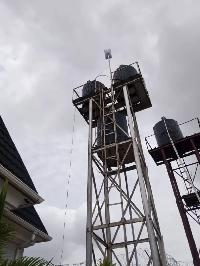 Water-tank tower with the Starlink pole at the top, beside the house